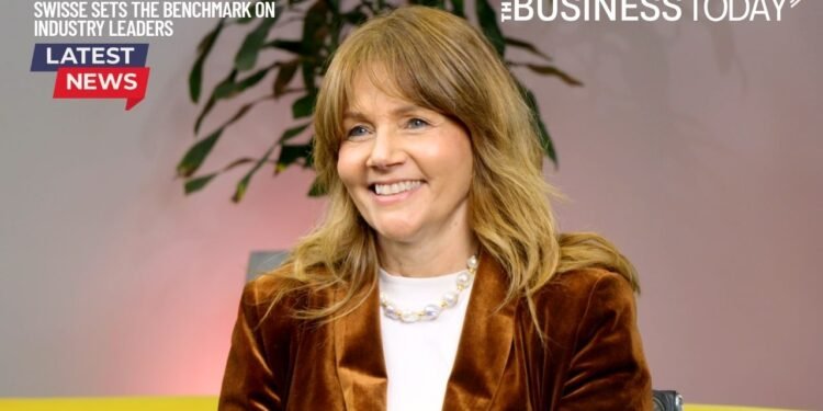 Rebecca Smith smiling during her Industry Leaders TV interview, seated in front of a soft-lit background with a plant in the frame.